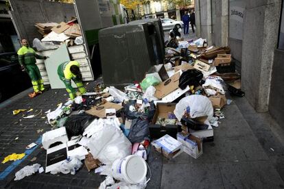 Dos operarios recogen basura en el barrio de Malasa&ntilde;a, en Madrid, tras la reciente huelga.