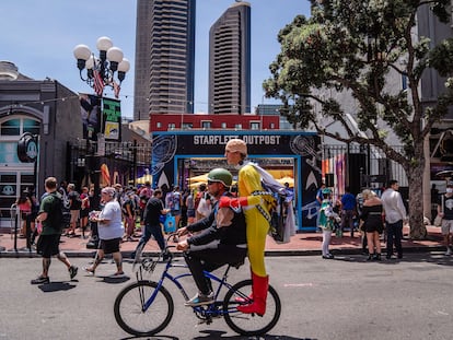 Un joven vestido como el héroe de 'One Punch Man' monta sobre una bicicleta en el centro de San Diego.