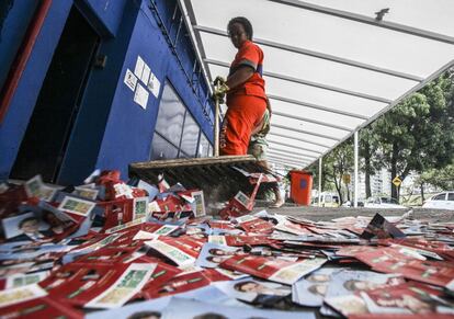 Uma gari varre os papéis de propaganda eleitoral nas ruas do Rio de Janeiro.