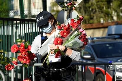 Una agente recupera flores dejadas en recuerdo de la funcionaria de policía asesinada el viernes en Rambouillet, en las afueras de París, en el último atentado terrorista en Francia