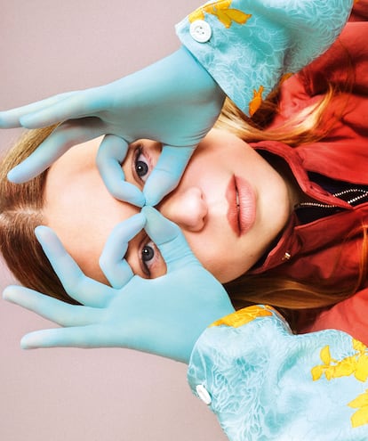 Léa Seydoux is wearing a floral zip-up blouse, a Utility vest, Blossom earrings and gloves, all by LOUIS VUITTON.