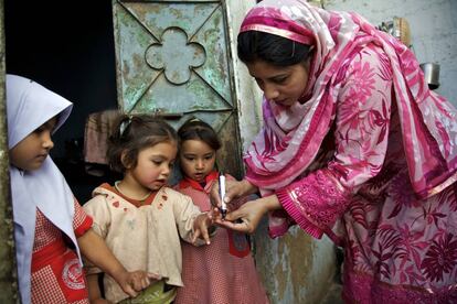 Una trabajadora sanitaria marca el dedo de una niña para indicar que ha sido vacunada contra la polio, en Karachi (Pakistán).