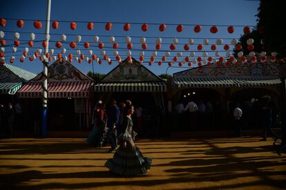 Una mujer vestida con el traje de sevillana pasa por delante de las casetas de la Feria de Abril, en Sevilla (España), el 6 de mayo de 2019.