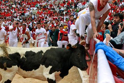 Un corredor salta hacia el callejón para evitar ser cogido por la vaquilla en la plaza de toros de Pamplona.