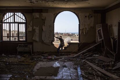 Un combatiente de las fuerzas libias afín al gobierno de Trípoli mira a través de una ventana en un edificio destrozado en la ciudad de Sirte (Líbia).