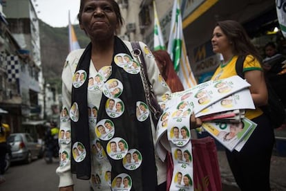 Una mujer distribuye botones a favor de la candidatura de Marina Silva en la favela de Rocinha, en Río de Janeiro.