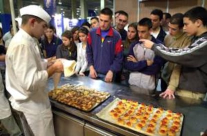 Un grupo de jovenes observa el trabajo de un pastelero durante la feria Emple$ 2001 que se ha inaugurado en Valencia en la que, además de ofertas de formación de diversos organismos, los jovenes visitantes pueden acceder a los 4.500 puestos de trabajo que ofertan las empresas participantes. EFE/Archivo