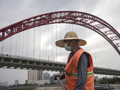 Un trabajador limpia la zona bajo el puente del río en Wuhan.