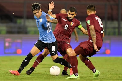 O jogador venezuelano Tomás Rincón (c) disputa a bola com Facundo Torres, do Uruguai, no dia 8 de junho em Caracas.