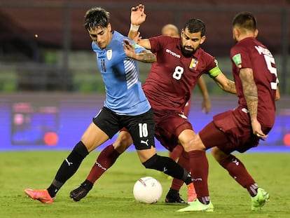 O jogador venezuelano Tomás Rincón (c) disputa a bola com Facundo Torres, do Uruguai, no dia 8 de junho em Caracas.