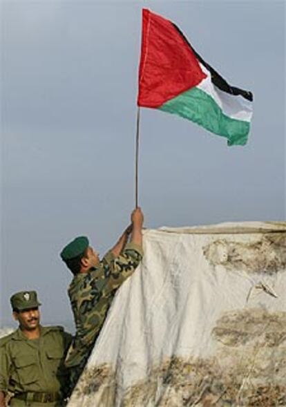 Fuerzas de seguridad palestinas colocan la bandera en un puesto de Gaza tras la retirada israelí.