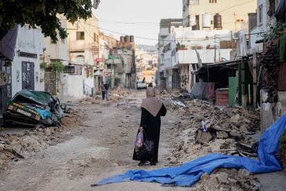 A Palestinian woman walks on a damaged road in the Jenin refugee camp in the West Bank, Wednesday, July 5, 2023