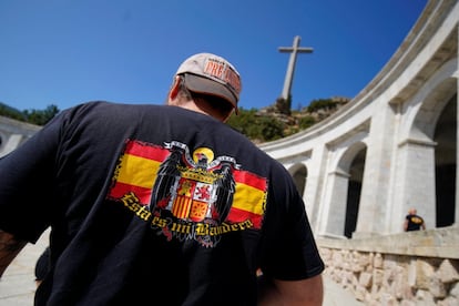 Un hombre con una camiseta que luce la bandera franquista frente al Valle de los Caídos. 