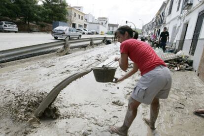 Una mujer retira el barro de su vivienda tras la tromba de agua que cayó ayer en Aguilar de la Frontera.