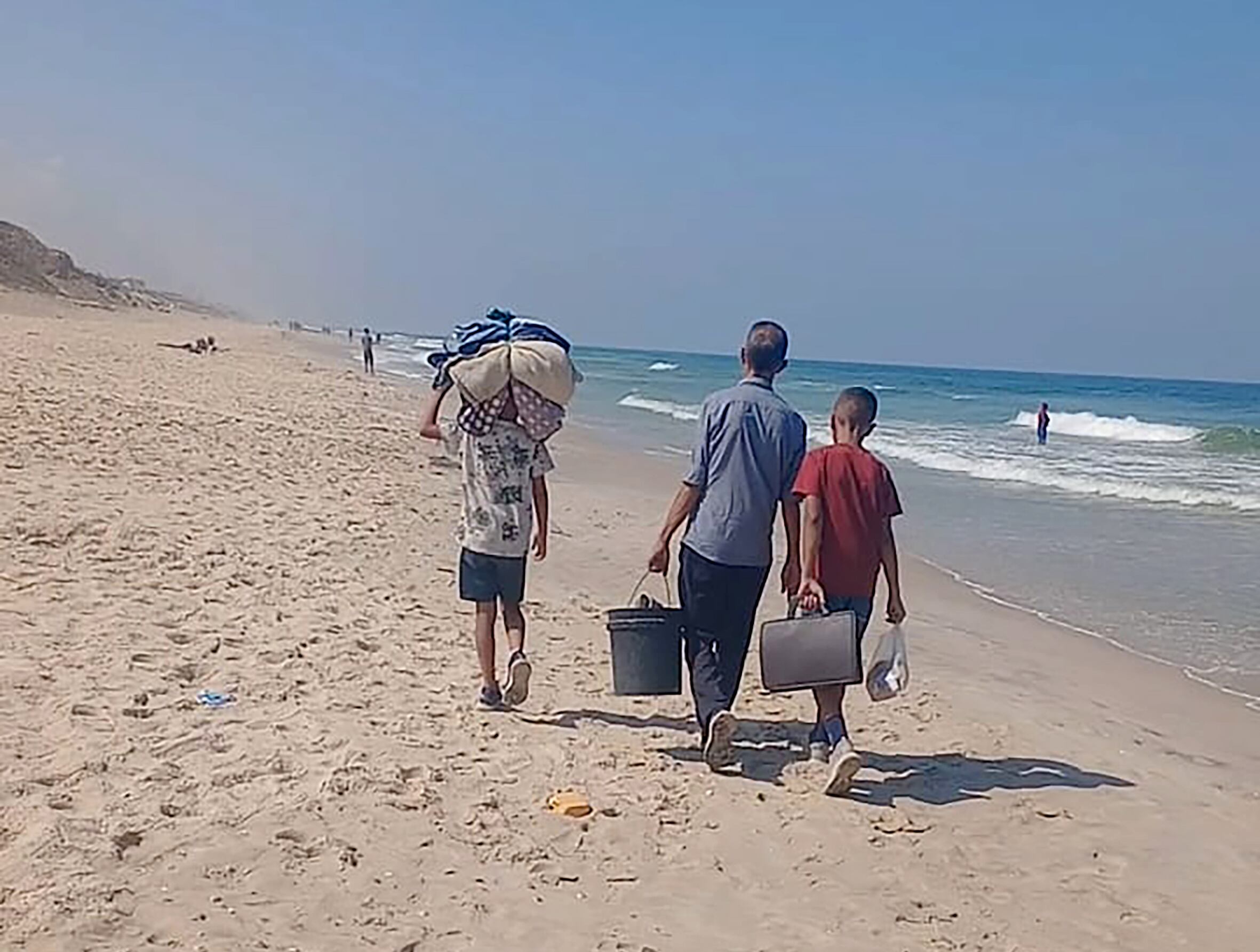 Husam Ghanem y sus dos hijos pequeños caminaban por la playa hacia el sur de Gaza después de abandonar su casa, esta semana.