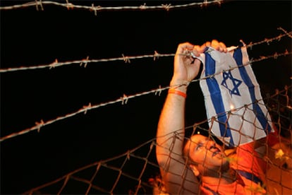 Un activista coloca una bandera israelí en la verja levantada por la policía en Kfar Maimón, al sur de Israel.