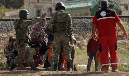Soldados turcos ayudan a civiles a atravesar la frontera por el puesto fronterizo de Ceylanpinar.
