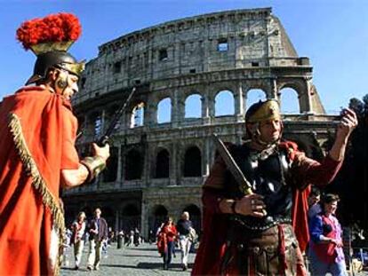 Dos hombres vestidos al estilo de los soldados romanos, ante el Coliseo.