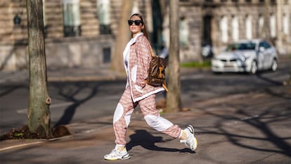 Una mujer en chándal con zapatillas caminando por la calle.