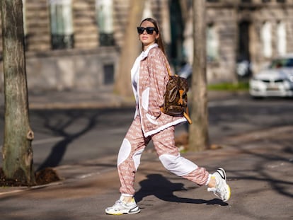 Una mujer en chándal con zapatillas caminando por la calle.