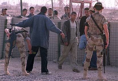 Soldados españoles cachean a iraquíes a la entrada de la  base de Diwaniya.