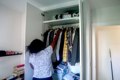 Una empleada de hogar organiza la ropa en un armario.