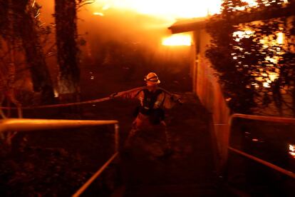 Un bombero lucha contra las llamas entre las viviendas de la ciudad californiana de Paradise (EE UU).