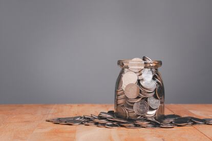 Saving planning with coins in a glass jar on wooden table over gray wall background with Save money concept for Financial Banking Business Ideas, Investments, Funds, Bonds, Dividends and Interest.