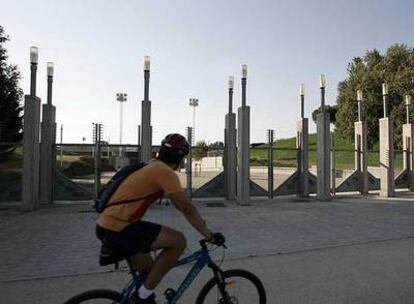 Un ciclista pasa por delante de la entrada del auditorio del parque Juan Carlos I, donde se habría celebrado el concierto.