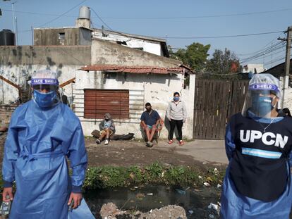 Dos trabajadores sanitarios, a principios de agosto con vecinos de Villa Fiorito (Buenos Aires, Argentina).