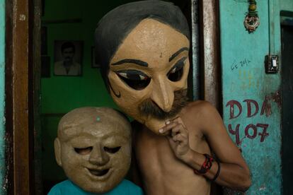 Dos niños juegan con caretas de marionetas en el barrio del arte y la magia.