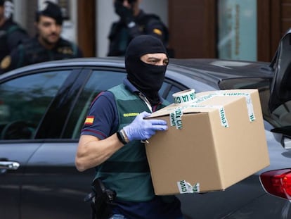 A Civil Guard officer takes material from one of the homes raided on Monday.