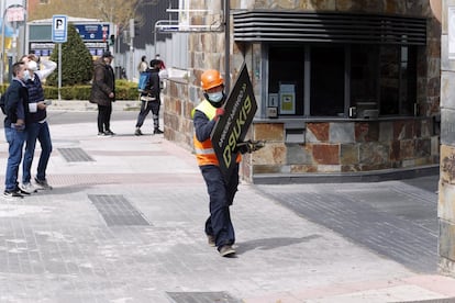 Un operario se lleva la cartelería del parkig de Bankia.