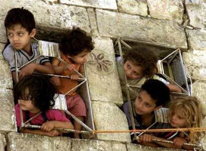 Niños palestinos se asoman por las ventanas de una vivienda durante un toque de queda en Hebrón en agosto de 2001.