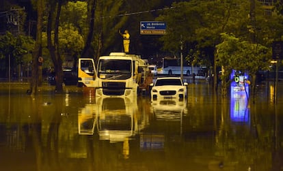 Un trabajador de una empresa de limpieza pública en la parte superior de un camión en mitad de una calle inundada, en el vecindario de Jardín Botánico.