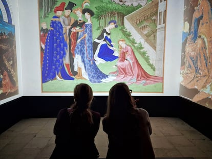 Dos personas mirando la proyección de las páginas del manuscrito 'Las Muy Ricas Horas' en la exposición en el castillo de Chantilly.