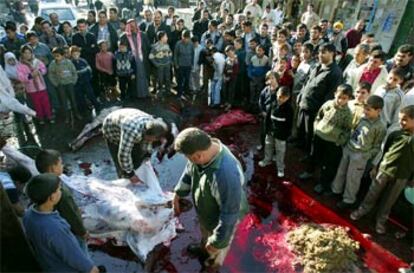 Niños palestinos observan cómo varios carniceros despiezan una res durante la fiesta del cordero.