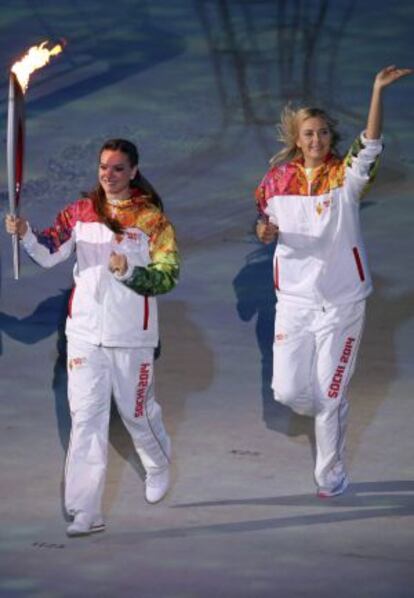 Las deportistas rusas Maria Sharapova (d) y Yelena Isinbayeva (i) portan la antorcha durante la ceremonia de inauguración de los XXII Juegos Olímpicos de Invierno en la ciudad rusa de Sochi