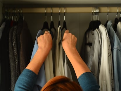 Una mujer toma perchas de un armario.