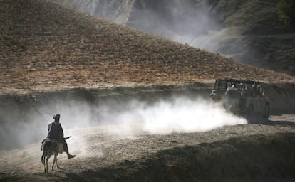 15 de septiembre de 2009. Un hombre afgano en su burro sigue a un convoy de soldados alemanes de la ISAF (Fuerza Internacional de Asistencia para la Seguridad) en la región montañosa de Faisabad, al este de Kunduz, Afganistán.