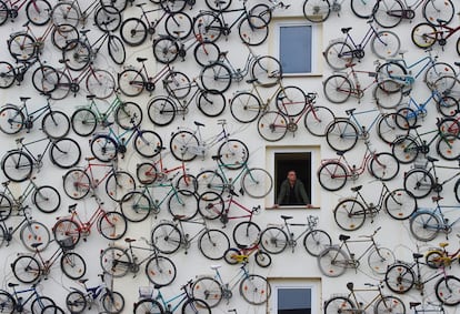 Un empleado de la llamada 'Estación de Bicicletas', observa por la ventana del edificio que tiene su fachada cubierta con bicicletas viejas en Altlandsberg (Alemania). La casa de alquiler de bicicletas y atracción turística tiene más de cien bicicletas en su pared.