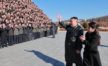 Kim Jong-un and reportedly his middle daughter greet a group of scientists working on the missile program, in an undated photo released on November 27 by the North Korean regime.