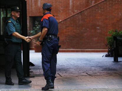 Un mosso d'esquadra saluda a un guardia civil en la entrada de la caserna de Travessera de Gracia, en Barcelona, donde permanecían varios de los 14 detenidos en Cataluña por delitos de malversación, prevaricación y desobediencia.