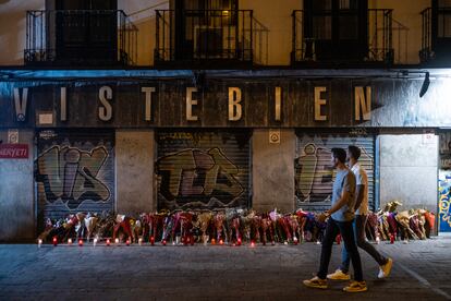 
Dos turistas pasan delante de las flores en homenaje a Conchi en la plaza de Tirso de Molina. 
