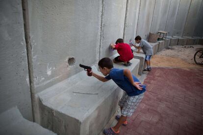 Niños israelíes juegan con armas de juguete entre unas paredes de cemento construidas para proteger el jardín del kibutz Nahal Oz, cerca de la frontera con la Franja de Gaza.