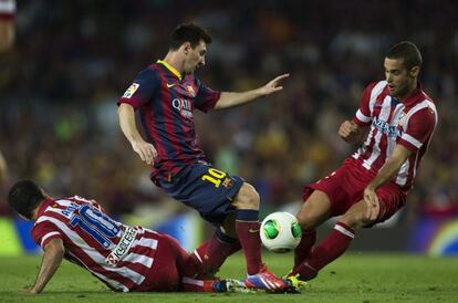 El davanter argentí lluita per la pilota amb el turc Arda Turan (a l'esquerra) i Mario Suárez (a la dreta), de l'Atlètic de Madrid, durant el partit de tornada de la Supercopa el 2013.