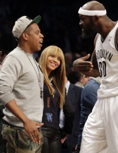 Jay-Z habla con el jugador de los Nets Reggie Evans ante la presencia de su esposa, la cantante Beyoncé.