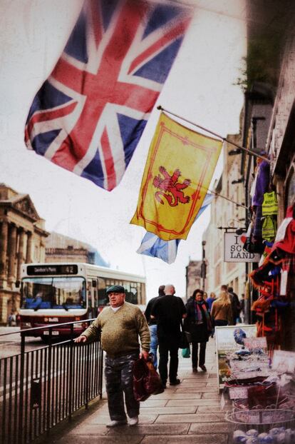 Un hombre camina bajo las banderas de Reino Unido y el 'León rampante', el símbolo del Reino de Escocia, por el centro de Edimburgo.