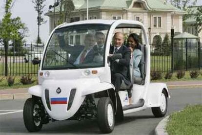 Putin conduce en San Petersburgo un coche eléctrico acompañado por Bush. Detrás, el ministro ruso de Defensa, Serguéi Ivanov, y Condoleezza Rice.