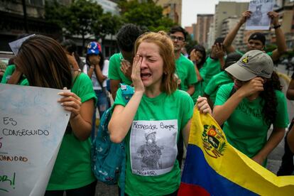 Venezolanos protestan mientras Trabajadores del Ministerio Público realizan el levantamiento planimétrico en el lugar en el que un joven de 17 años murió durante una protesta opositora, en Caracas (Venezuela). 